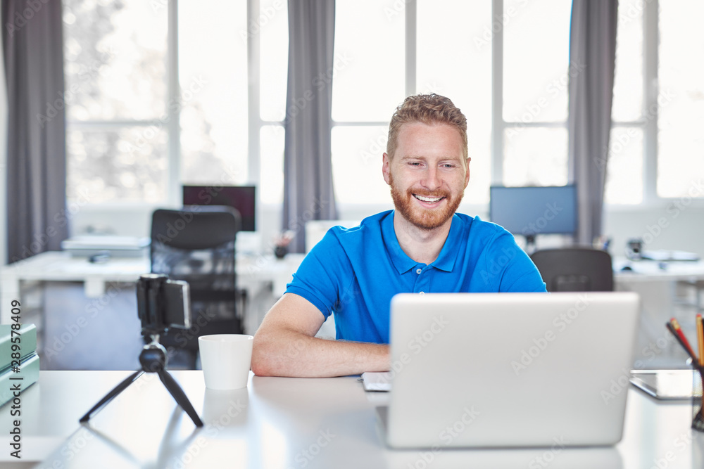 Young Caucasian employee sitting in office and typing on laptop. Start up business concept. Young Caucasian employee sitting in office and typing on laptop. Start up business concept.