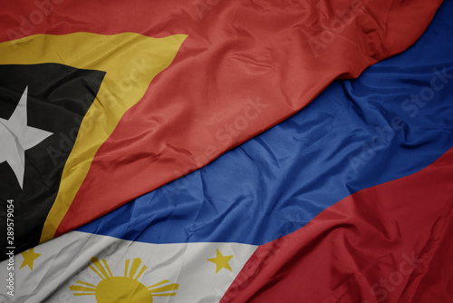 waving colorful flag of philippines and national flag of east timor.