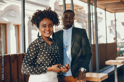 A young and stylish dark-skinned couple standing in a sunny city photo