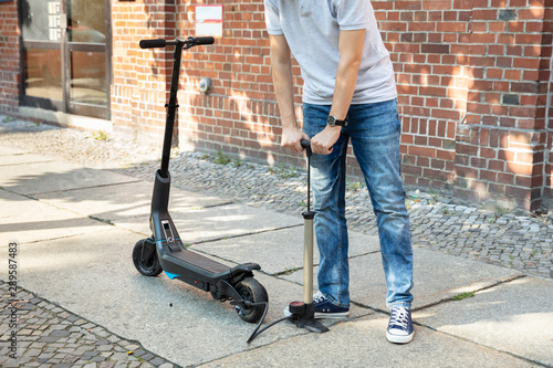 Man Pumping Air Into Tire On E-Scooter