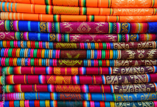 A pile of colorful traditional textiles in the Andes mountain range sunday market of Otavalo, north of Quito, Ecuador. photo