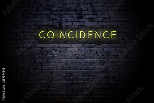 Highlighted brick wall with neon inscription coincidence