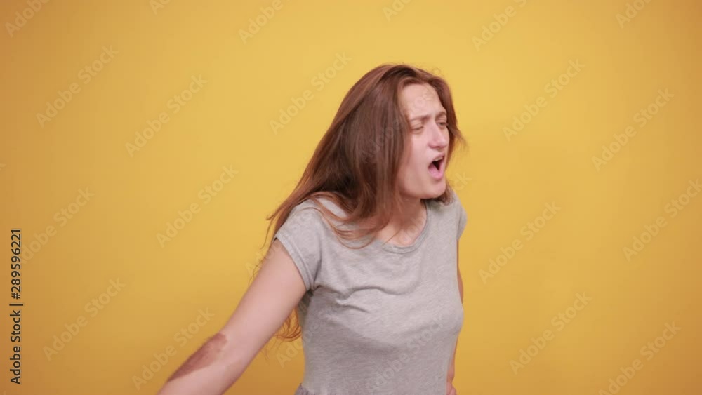 brunette girl in gray t-shirt over isolated orange background shows emotions brunette girl in gray t-shirt over isolated orange background shows emotions