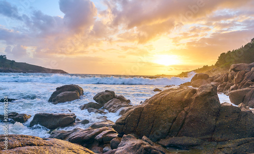 Sunset of the sea with rocks and mountain in the background. Beach and sea water with long exposure.