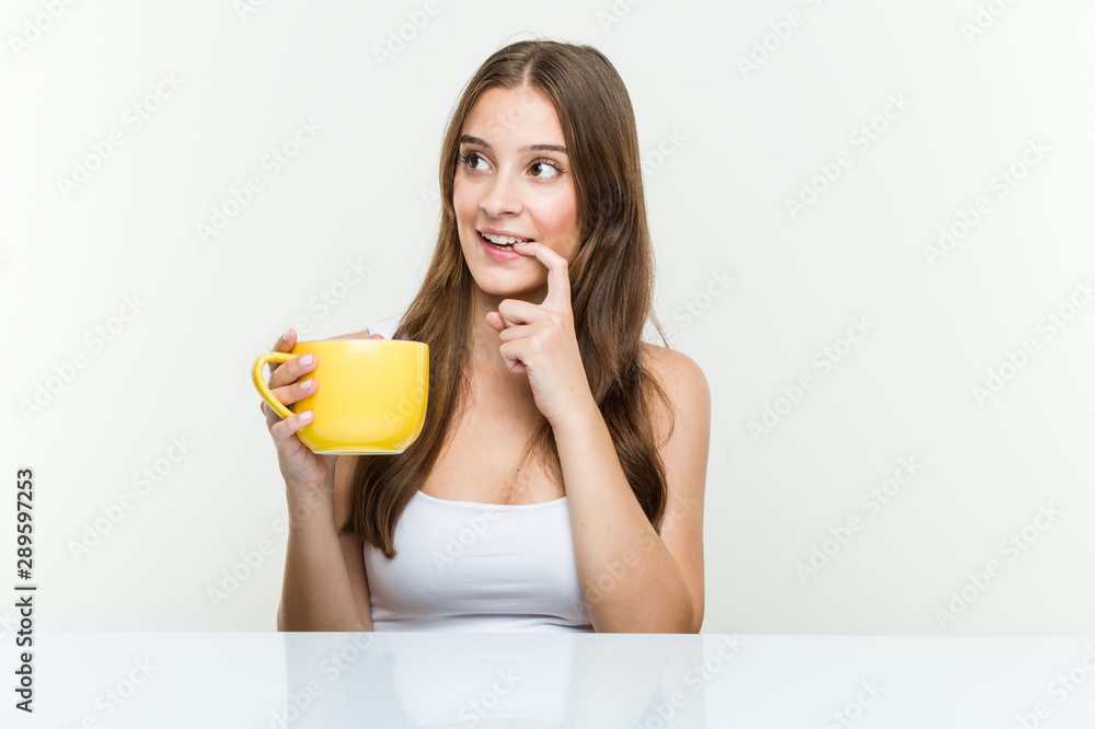 Young caucasian woman holding a cup relaxed thinking about something looking at a copy space. Young caucasian woman holding a cup relaxed thinking about something looking at a copy space.