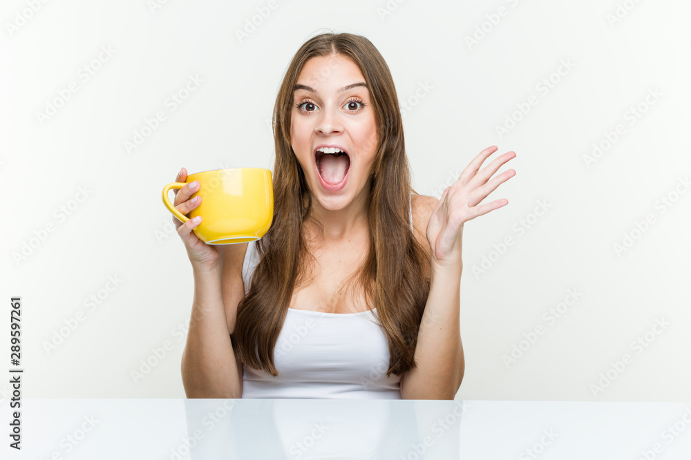 Young caucasian woman holding a cup celebrating a victory or success Young caucasian woman holding a cup celebrating a victory or success