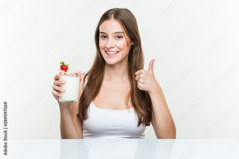 Young caucasian woman holding a smoothie smiling and raising thumb up Young caucasian woman holding a smoothie smiling and raising thumb up