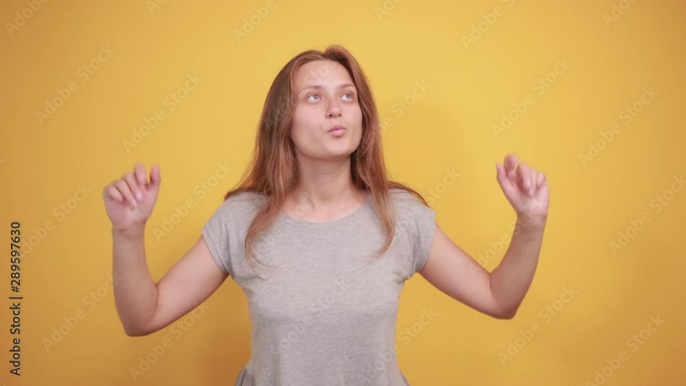 brunette girl in gray t-shirt over isolated orange background shows emotions brunette girl in gray t-shirt over isolated orange background shows emotions