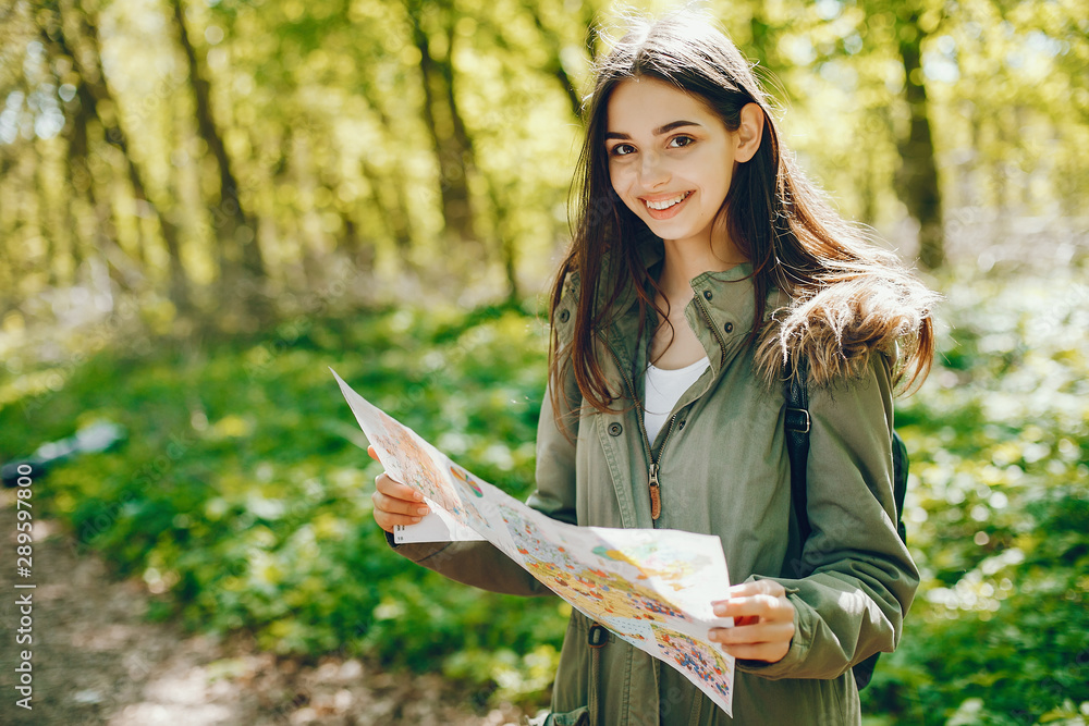 Cute girl standing in a autumn forest. Lady use the map Cute girl standing in a autumn forest. Lady use the map