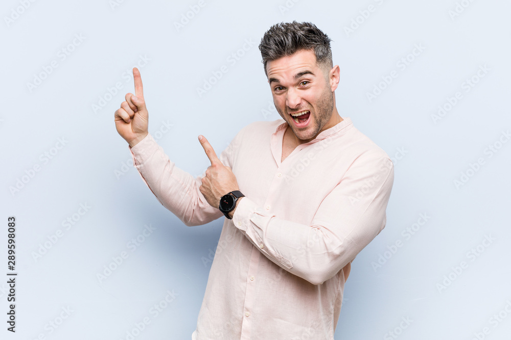 Young handsome cool man pointing with forefingers to a copy space, expressing excitement and desire. Young handsome cool man pointing with forefingers to a copy space, expressing excitement and desire.
