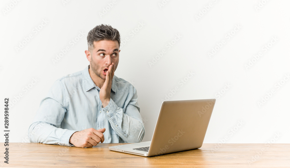 Young handsome man working with his laptop is saying a secret hot braking news and looking aside Young handsome man working with his laptop is saying a secret hot braking news and looking aside