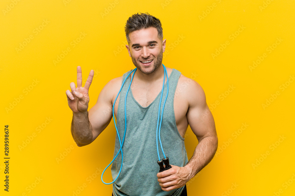 Caucasian man holding a jump rope showing victory sign and smiling broadly. Caucasian man holding a jump rope showing victory sign and smiling broadly.