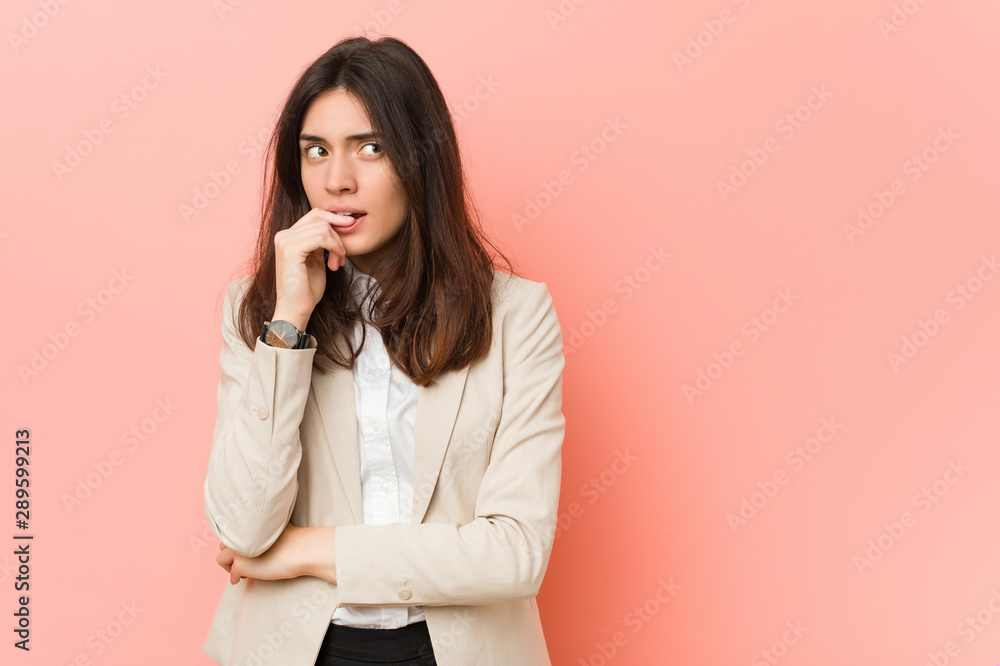 Young brunette business woman against a pink background relaxed thinking about something looking at a copy space. Young brunette business woman against a pink background relaxed thinking about something looking at a copy space.