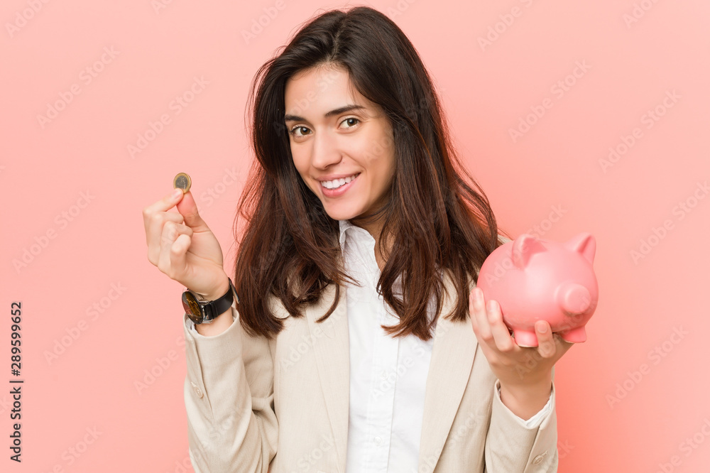 Young caucasian woman holding a piggy bank - obrazy, fototapety, plakaty 