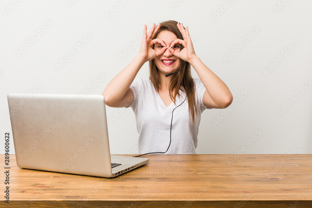 Young telemarketer woman showing okay sign over eyes Young telemarketer woman showing okay sign over eyes