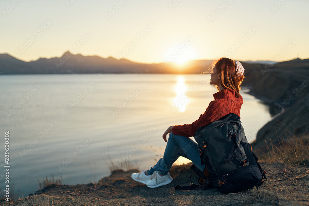 woman sitting on rock at sunset