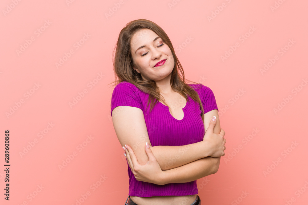 Young hispanic woman against a pink wall hugs, smiling carefree and happy. Young hispanic woman against a pink wall hugs, smiling carefree and happy.