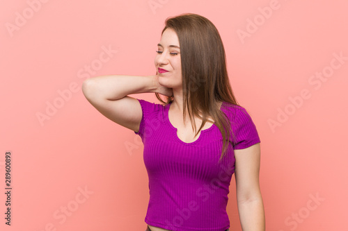 Young hispanic woman against a pink wall suffering neck pain due to sedentary lifestyle.