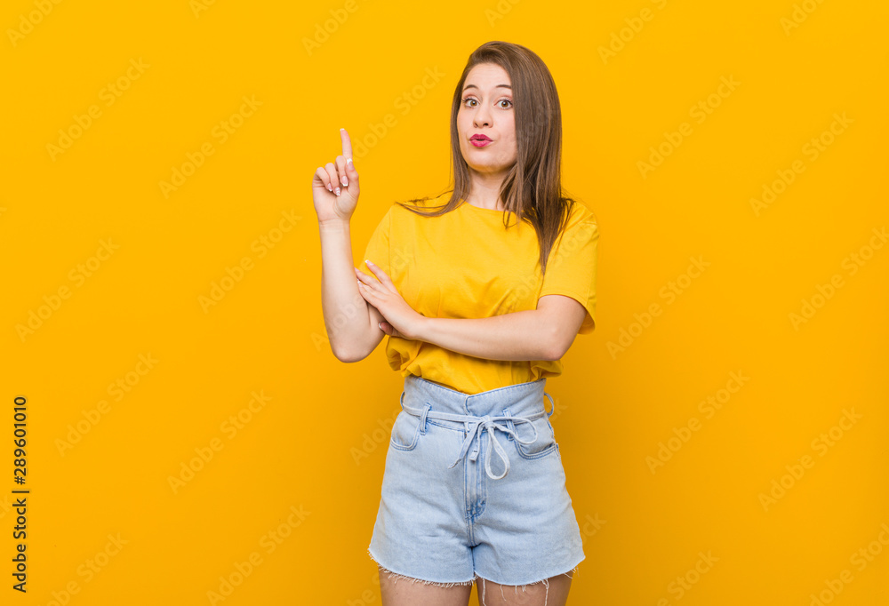 Young woman teenager wearing a yellow shirt having some great idea, concept of creativity. Young woman teenager wearing a yellow shirt having some great idea, concept of creativity.