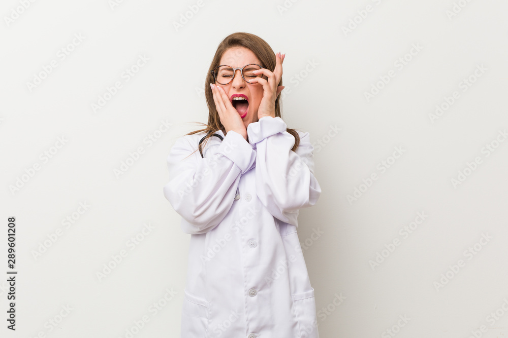 Young doctor woman against a white wall whining and crying disconsolately. Young doctor woman against a white wall whining and crying disconsolately.