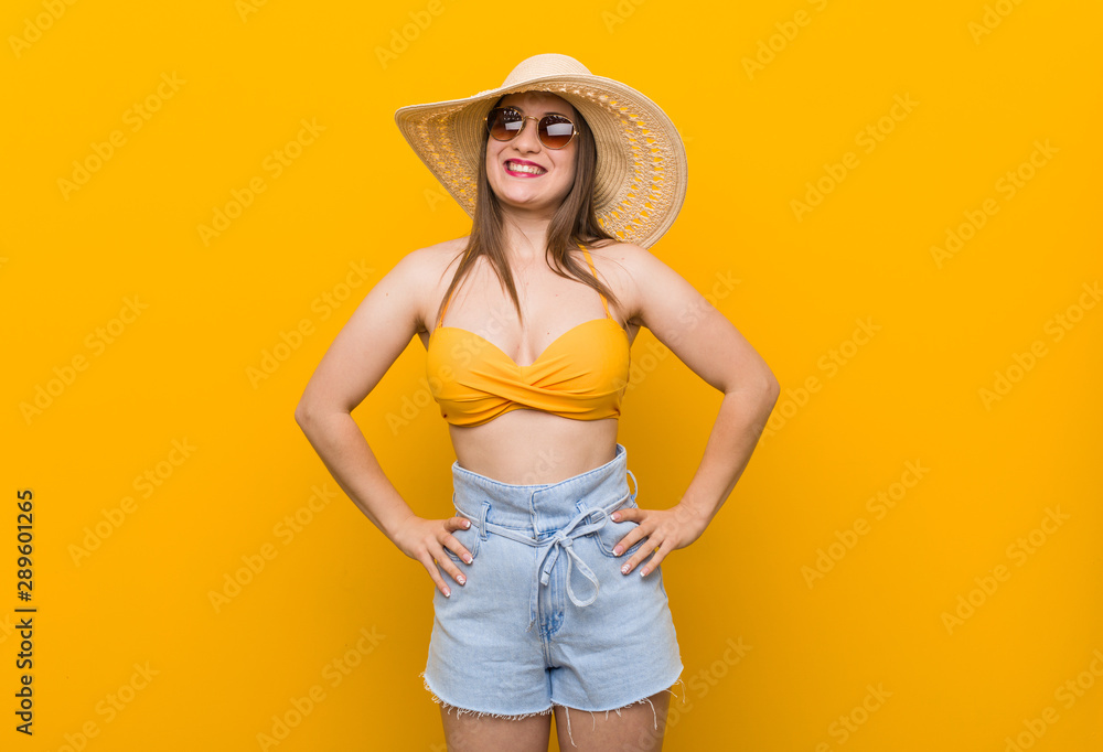 Young caucasian woman wearing a straw hat, summer look confident keeping hands on hips. Young caucasian woman wearing a straw hat, summer look confident keeping hands on hips.