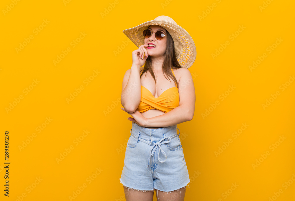 Young caucasian woman wearing a straw hat, summer look relaxed thinking about something looking at a copy space. Young caucasian woman wearing a straw hat, summer look relaxed thinking about something looking at a copy space.
