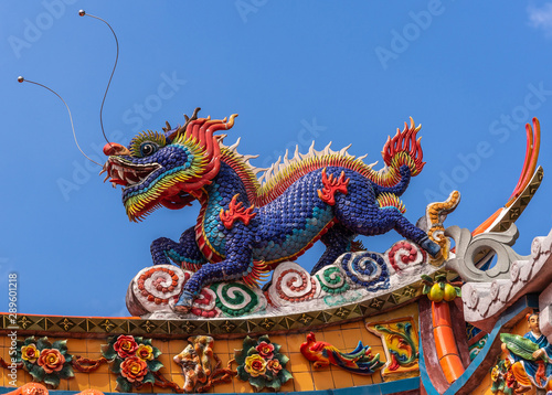 Manila, Philippines - March 5, 2019: Chinese Cemetery in Santa Cruz part of town. Closeup of dragon at colorful and extensively decorated top of main gate to temple and ceremonial hall. Blue sky. photo