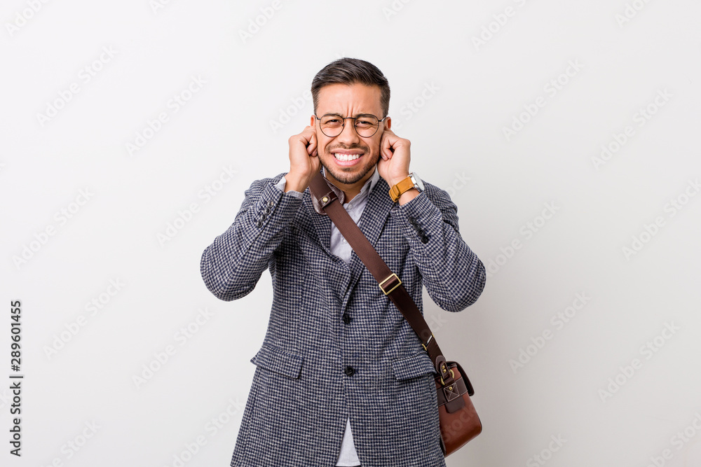 Young business filipino man against a white wall covering ears with hands. Young business filipino man against a white wall covering ears with hands.