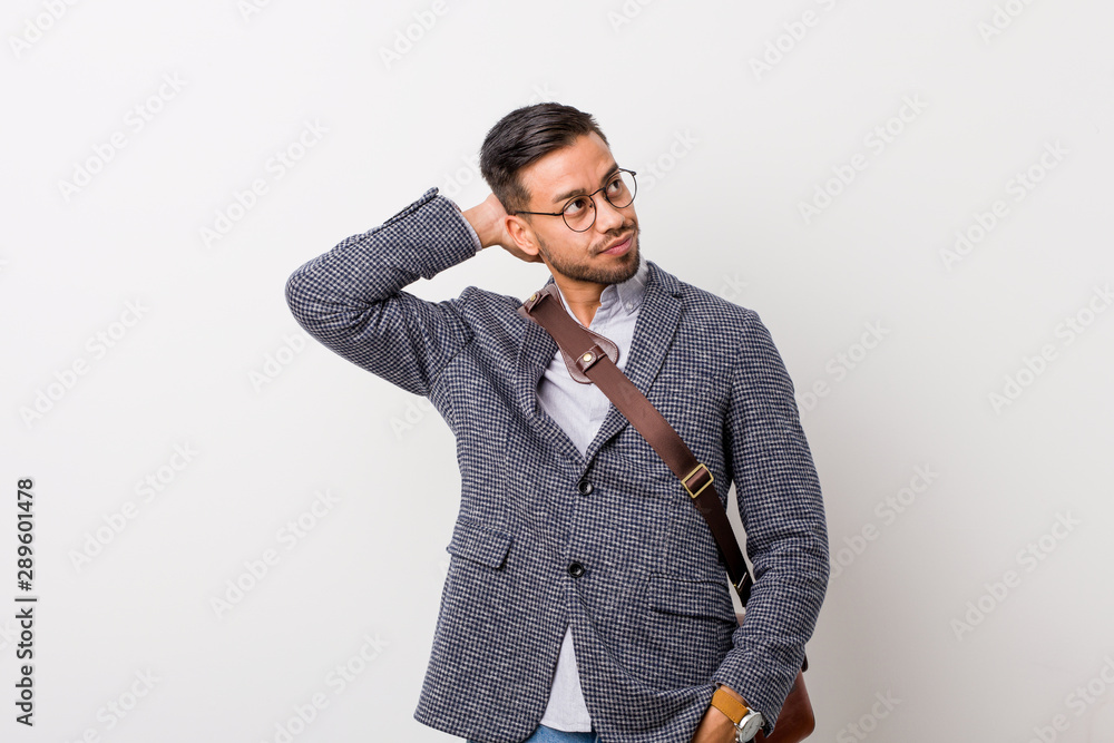 Young business filipino man against a white wall touching back of head, thinking and making a choice. Young business filipino man against a white wall touching back of head, thinking and making a choice.