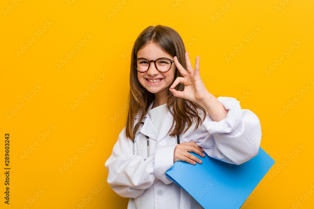 Little caucasian girl wearing a doctor costume cheerful and confident showing ok gesture. Little caucasian girl wearing a doctor costume cheerful and confident showing ok gesture.