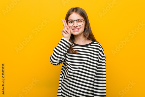 Little caucasian cute girl showing victory sign and smiling broadly.