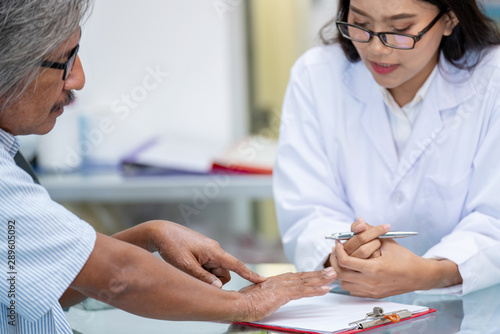 Blurred focus senior asian man patient meet woman pharmacist or doctor to advise about his dermatitis allergic hand with flaking dry itchy skin conditions and peeling at pharmacy drugstore clinic