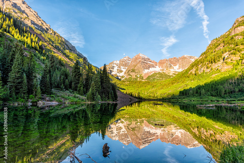 Maroon Bells lake at sunrise in Aspen, Colorado with rocky mountain peak and snow in July 2019 summer and vibrant light reflection on water