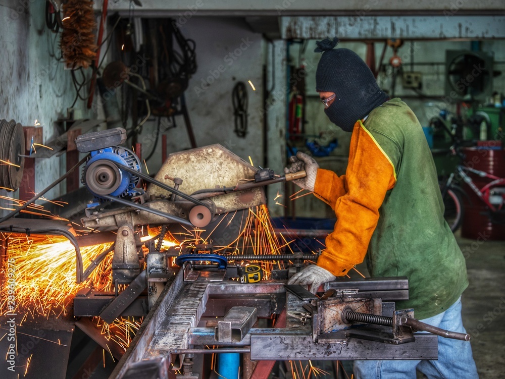 worker grinding cutting metal sheet with grinder machine overwrites the master of welding seams angle grinder and sparks. Electric grinder in the industrial worker grinding cutting metal sheet with grinder machine overwrites the master of welding seams angle grinder and sparks. Electric grinder in the industrial