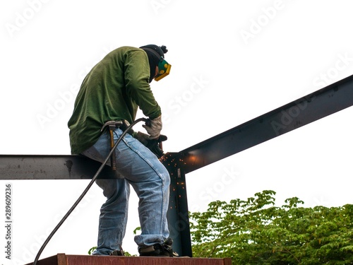 worker grinding cutting metal sheet with grinder machine overwrites the master of welding seams angle grinder and sparks. Electric grinder in the industrial  photo