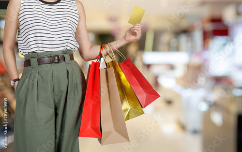 Shopping woman holding shopping bags and credit card in the mall store blurred background, E-commerce digital marketing lifestyle concept