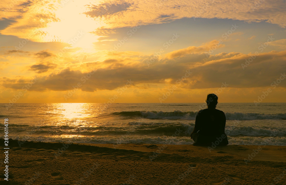  Indian woman meditating on morning sunrise beach