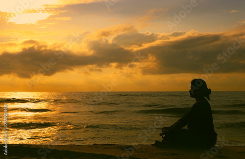  Indian woman meditating on morning sunrise beach
