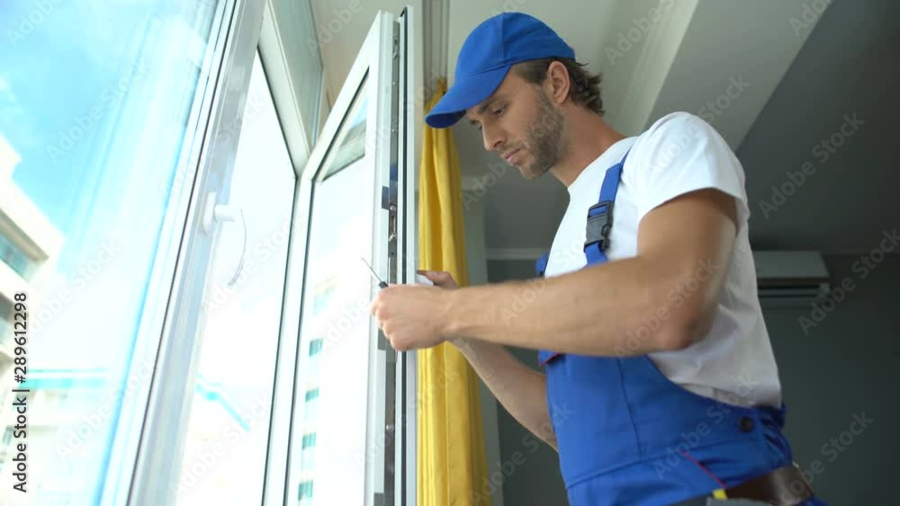 Handyman using screwdriver to fix window, repair and installation services Handyman using screwdriver to fix window, repair and installation services