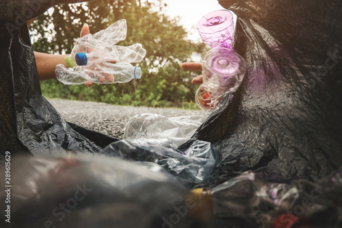 The volunteer picking up a bottle plastic in to a bin bag for cleaning, volunteering concept. Environmental pollution and Ecological problem. photo