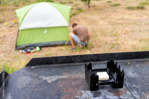 Campsite with background of man setting up tent and closeup of camp stove on grill on Canyon Rim Campground in Flaming Gorge Utah National Park photo