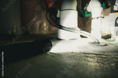 flashlight shining light on sump pump system