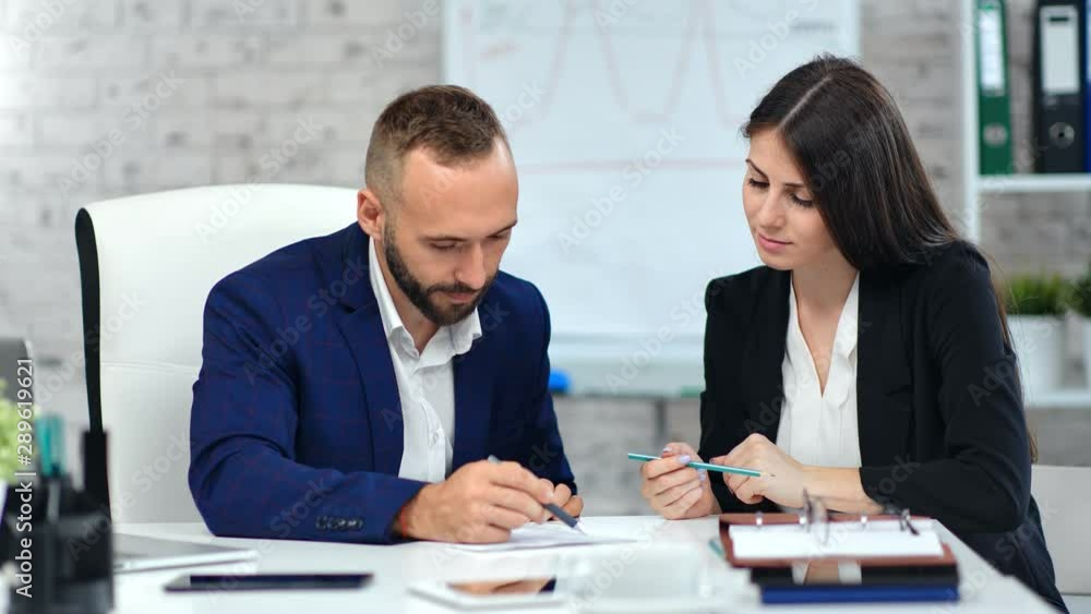 Male boss making signature on paper contract agreement using pen looking on data at workplace Male boss making signature on paper contract agreement using pen looking on data at workplace