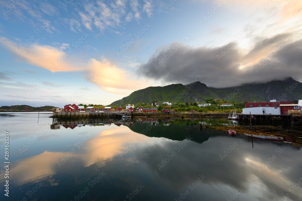 Fishing boat and red village Reflecting the water in the evening at Ballstad, Northern Norway, Rorbu is the traditional home of Norwegian fishermen.