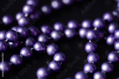 Long beaded necklace purple color on a dark background close up