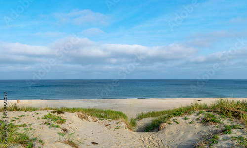 landscape with white sand dunes and beautiful blue sea, wooden footpaths