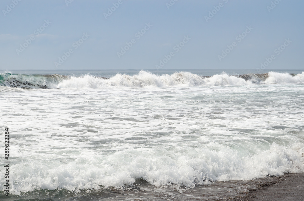 Waves breaking on black sand beach
