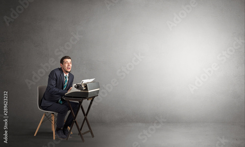Man working hard on a typewriter in an empty space