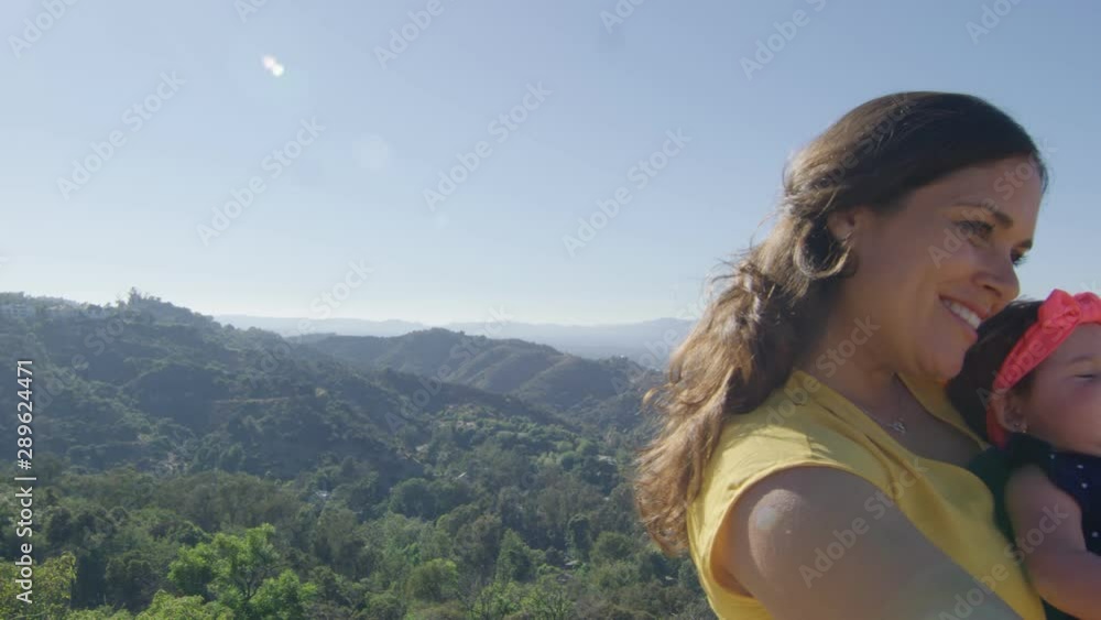 Slow motion of mother taking selfie with baby by mountains Slow motion of mother taking selfie with baby by mountains