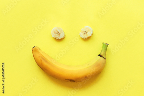 Banana on a yellow background in the form of a smile, top view, flat lay.